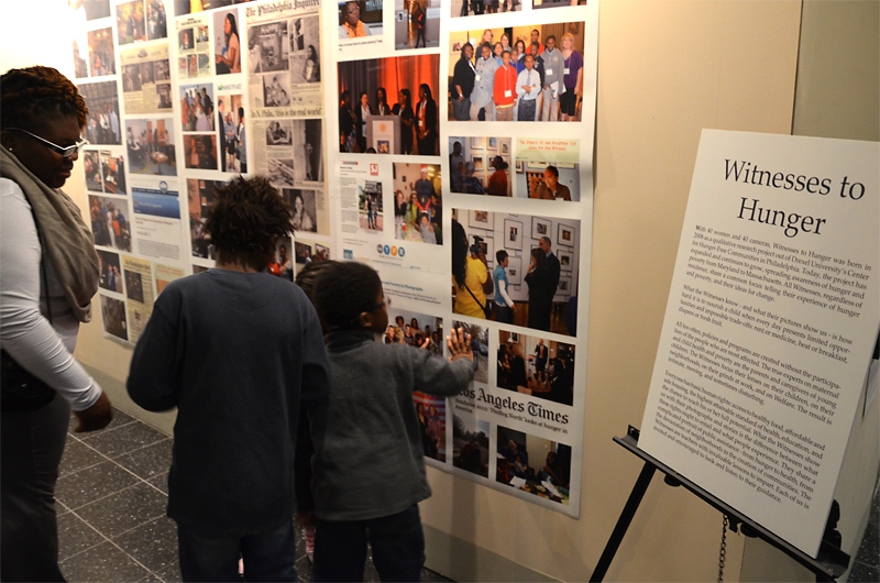 Tianna, a participant in Witnesses to Hunger, reviews some of the program's accomplishments with her children at the program's five-year anniversary exhibit.